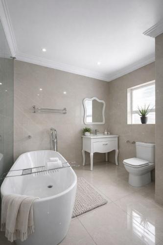 a bathroom with a tub and a toilet and a sink at The Seamless Oasis in Cape Town