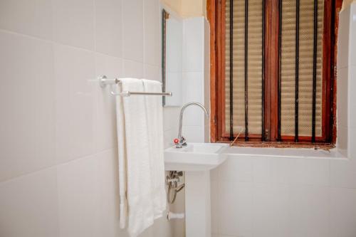a white bathroom with a sink and a window at Cathedral Hotel Zanzibar in Zanzibar City