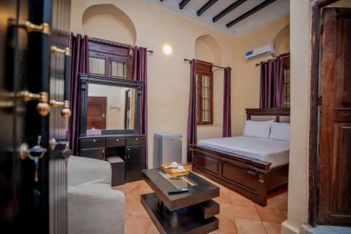 a bedroom with a bed and a table and a couch at Cathedral Hotel Zanzibar in Zanzibar City