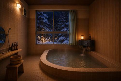 a bathroom with a bath tub with a window with snow at LUX Niseko lodge in Niseko