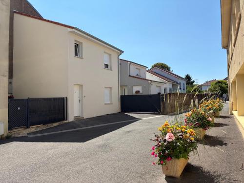 a row of houses with flowers in pots on a driveway at Appart orange 25 m2 neuf RDC in Sainte-Marie-aux-Chênes