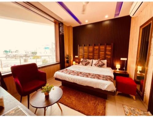 a bedroom with a large bed and a red chair at Hotel PG Grand in Mohali