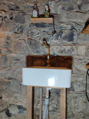 a sink in a stone wall with a faucet at Mühle am Sandbach in Niedererbach