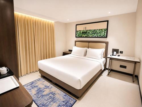 a bedroom with a large white bed and a desk at Toshali Sands Puri in Puri