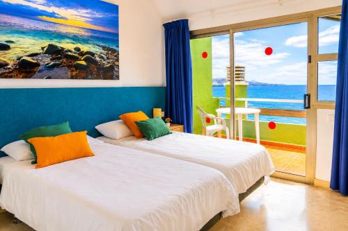 two beds in a room with a view of the ocean at Brisamar Canteras in Las Palmas de Gran Canaria