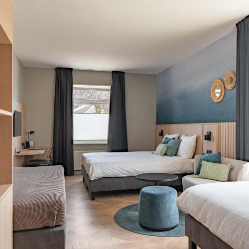a hotel room with two beds and a couch at Hotel de Gentsche Poort in Biervliet