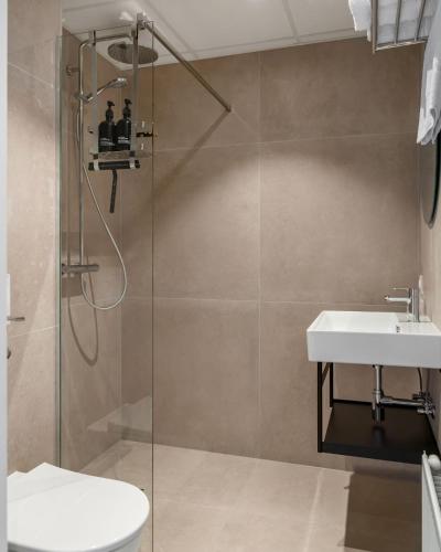 a bathroom with a shower and a toilet and a sink at Hotel de Gentsche Poort in Biervliet
