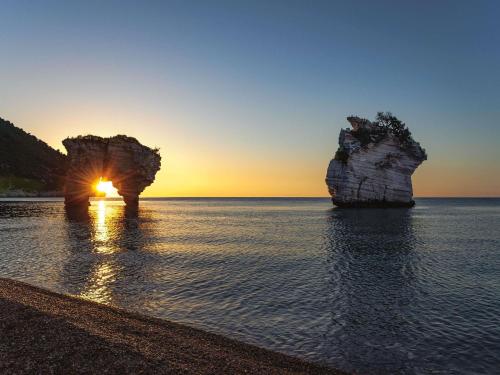 two large rocks in the water at sunset at Baia Delle Zagare - Handwritten Collection in Mattinata