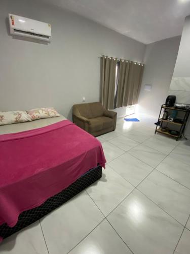 a bedroom with a pink bed and a chair at silencioso e aconchegante in Rio Verde