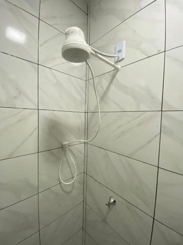 a shower with a light on a white tiled wall at silencioso e aconchegante in Rio Verde