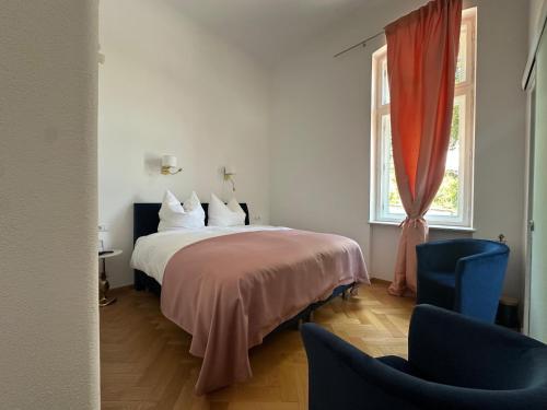 a bedroom with a bed and two chairs and a window at Vila Popovici in Prăjila