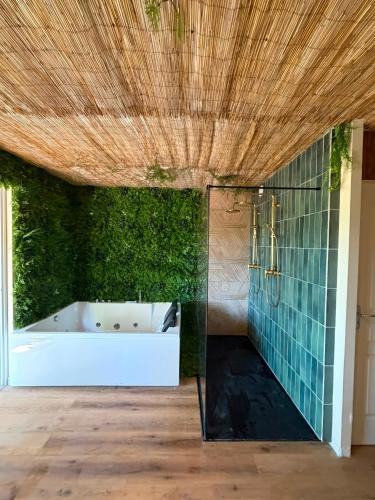 a bathroom with a tub and a green wall at L'EVIDENCE Love Room & spa in Chaveignes