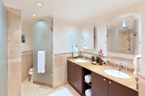 a bathroom with two sinks and a large mirror at Modern Beachfront Condo with Pool - Sapphire 307 in Christ Church