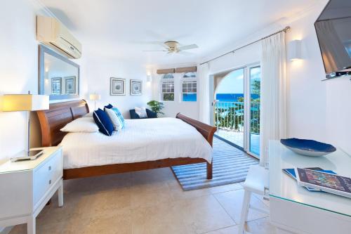 a bedroom with a bed and a balcony with the ocean at Modern Beachfront Condo with Pool - Sapphire 307 in Christ Church