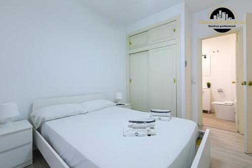 a white bedroom with a white bed and a bathroom at El Bajondillo Apartment in Torremolinos