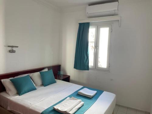 a bed with blue and white pillows and a window at Villa Nergis in Bitez