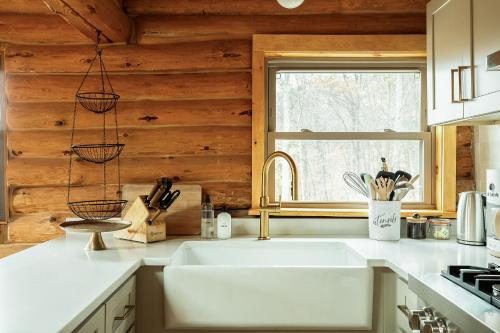 a kitchen with a white sink and a window at Fawn Hill Elevated Log Cabin w Year-Round Pool in Phoenicia