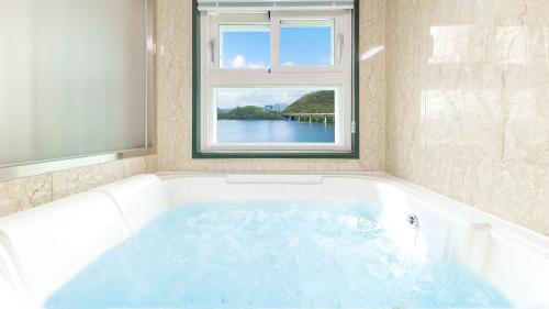 a large bath tub with a window in a bathroom at Chuncheon El Dorado Kid's Pension in Gapyeong