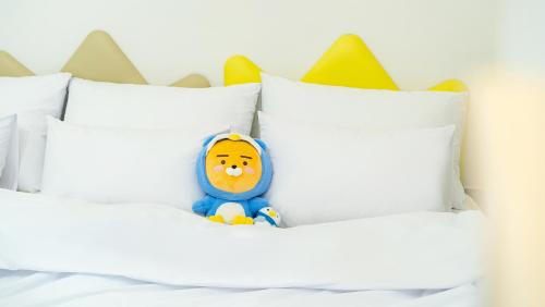 a toy in the middle of a bed with white pillows at Chuncheon El Dorado Kid's Pension in Gapyeong