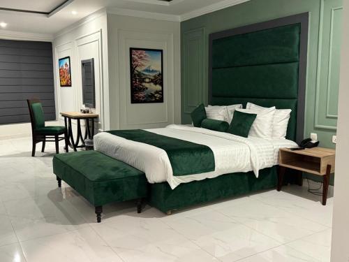 a bedroom with a large green bed and a table at Hotel the Jeeven's in Sialkot