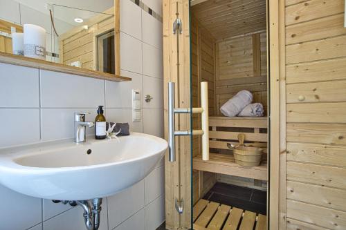 a bathroom with a white sink and wooden walls at Ferienhaus Immenhof in Rieden