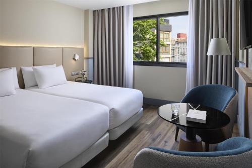 a hotel room with a bed and a desk and a chair at NH Ciudad de Santander in Santander