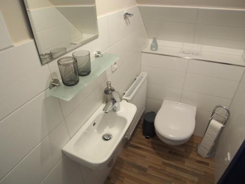 a white bathroom with a sink and a toilet at Ferienwohnung Strandkrabbe Ockholm in Ockholm