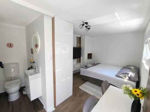 a small white room with a bed and a bathroom at El Higo Apartments in Mostar