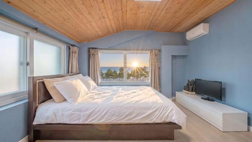 a bedroom with a bed and a large window at Goseong Omaju Pension in Goseong