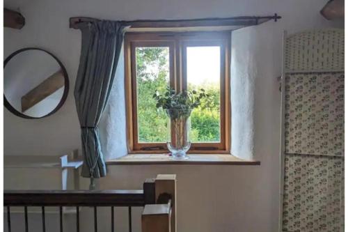a window with a vase with a plant in it at 1 Bed Barn - Sleeps 2 - Pool - Garden - Bbq in Taunton