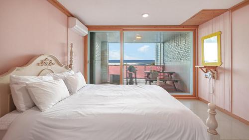 a bedroom with a white bed and a balcony at Yangyang Bono Pet-friendly Pension in Yangyang