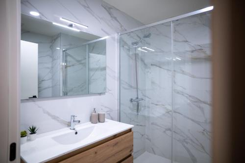 a white bathroom with a sink and a shower at La Maison de Ré in Vila Real