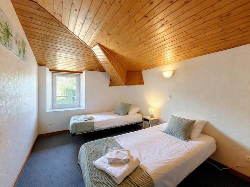 a bedroom with two beds and a wooden ceiling at Le Cornas in Vérin