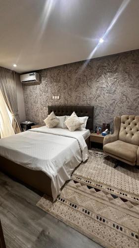 a bedroom with a large bed and a chair at Residence 541 Apartments and Suites in Abuja