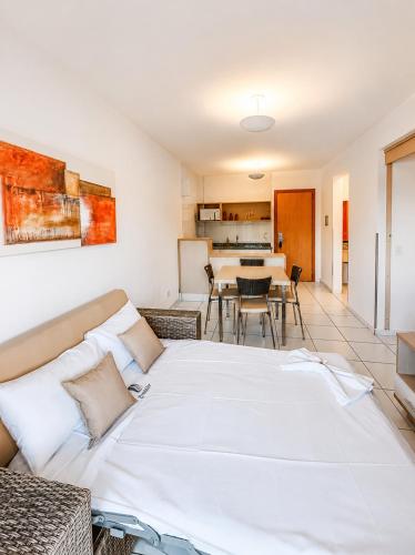 a living room with a large bed and a kitchen at Pontal do Lago Flat Residence, aproveite dias incríveis em família às margens do lago Corumbá in Caldas Novas