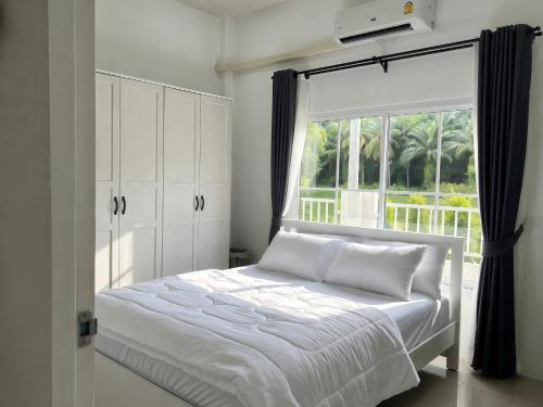 a bedroom with a white bed and a window at เอกสิริ รีสอร์ต in Amphoe Tha Chana