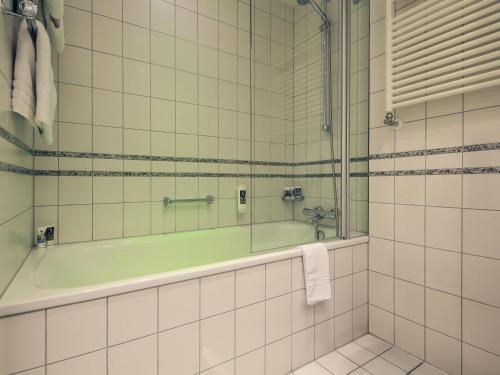 a bathroom with a bath tub and a sink at Mercure Hotel Plaza Essen in Essen