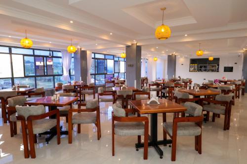 a restaurant with wooden tables and chairs and windows at Maraluxe Resoert & Spa in Nakuru