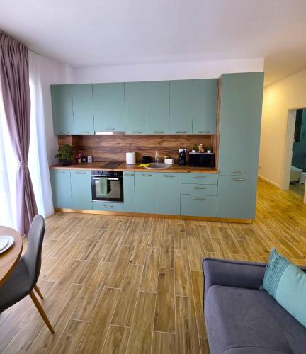 a kitchen with blue cabinets and a wooden floor at Sakura Residence Felix in Sînmartin