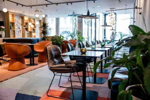 a restaurant with tables and chairs and plants at Motel One Amsterdam in Amsterdam