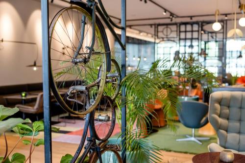 a bike hanging from a pole in a room with plants at Motel One Amsterdam in Amsterdam