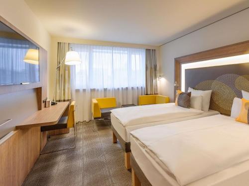 a hotel room with two beds and a television at Novotel München City Arnulfpark in Munich