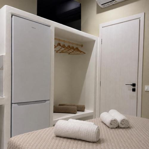 a white bedroom with two towels on a bed at Pelekouda Coastal Apartments in Pollonia