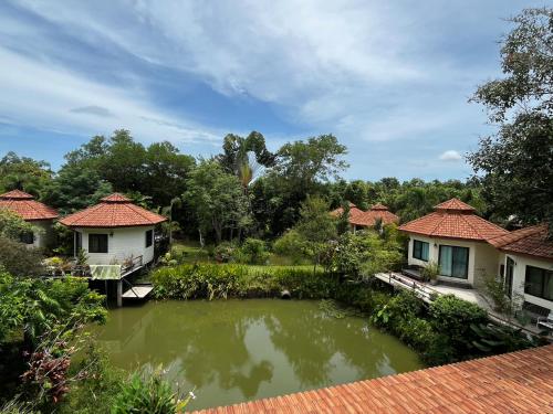 a pond in a garden with houses and trees at Navari Homestay in Rayong