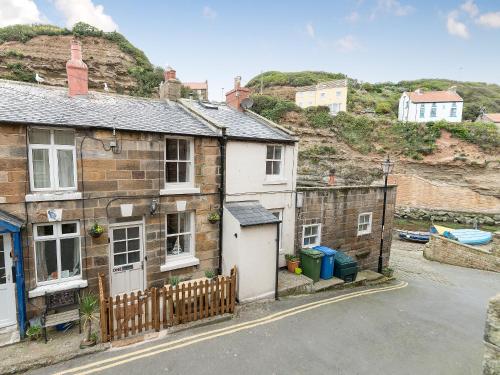 a house with a fence next to a street at One Beckside Cottage in Staithes