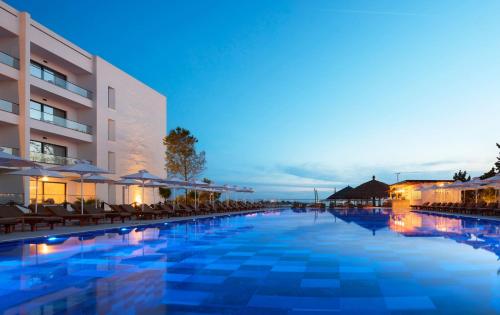 a swimming pool with chairs and umbrellas next to a building at SOL by Meliá Tropikal Durres in Durrës