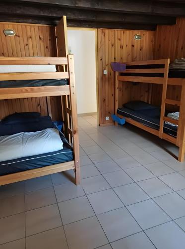 a room with bunk beds and a tiled floor at Gîte proche de La Salvetat in Le Soulié
