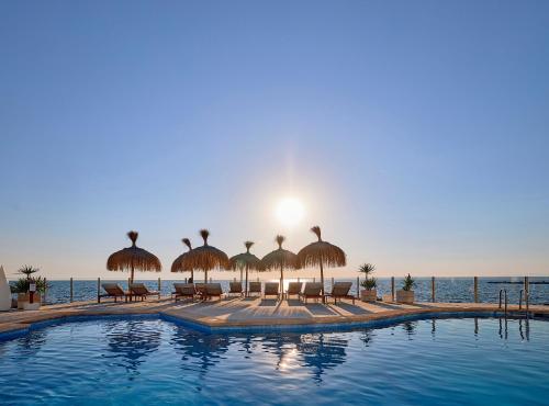 ein Swimmingpool mit Sonnenschirmen und Liegestühlen und das Meer in der Unterkunft Universal Hotel Cabo Blanco - Adults Only in Colonia Sant Jordi