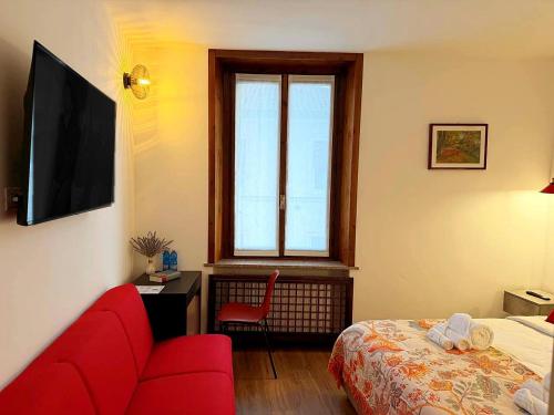 a room with a red couch and a bed and a window at "The Moment"- rooms Bergamo center, self check-in, late Arrivals in Bergamo