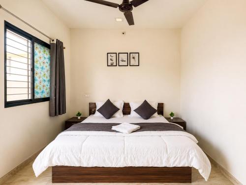 a bedroom with a bed with white sheets and a window at Hotel Tiger Paradise in Mahirāvani